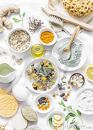 Home beauty products - clay, oatmeal, coconut oil, turmeric, lemon, scrub, dry flowers and herbs, sponges, soap, facial brush on l Stock Photo