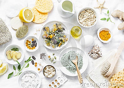 Home beauty products - clay, oatmeal, coconut oil, turmeric, lemon, scrub, dry flowers and herbs, sponges, soap, facial brush on l Stock Photo