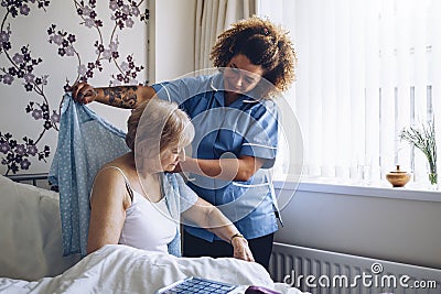 Home caregiver dressing senior Stock Photo