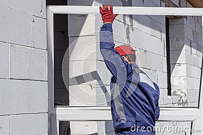 Home construction loader worker carries a platic window for installation Stock Photo