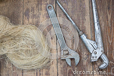 Home craftsman`s tool. Top view wrenches, adjustable wrench, pipe wrench, plumbing flax on wooden vintage background. Home plumbi Stock Photo