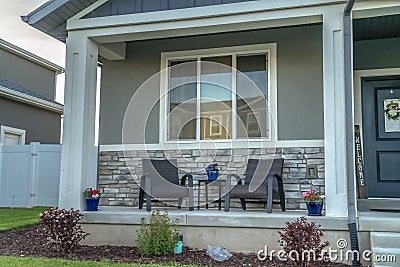 Home facade with porch and front door decorated with potted plants and wreath Stock Photo