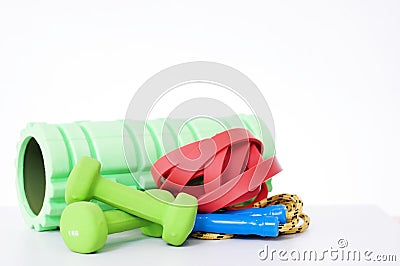 Home fitness equipment isolated on white background. foam roller, elastic band,jump rope, dumbbell for body workout Stock Photo