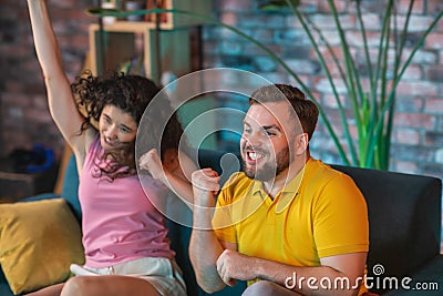 At home in front of tv good looking couple watching a football match together they getting happy when their team are Stock Photo