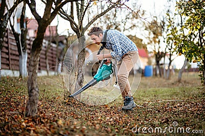 Home gardening details, man cleaning up the garden using leaf blower Stock Photo