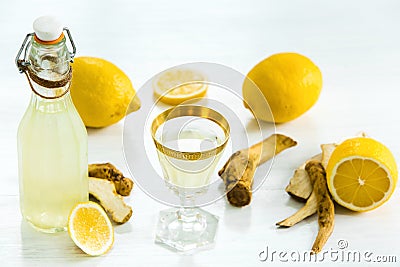 Home ginger tincture in a glass and fresh lemons on the white wooden background Stock Photo