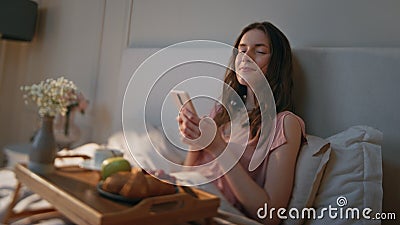 Home girl using smartphone in cozy bedroom closeup. Relaxed smiling woman look Stock Photo