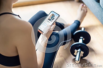 Home gym workout with online exercise app in phone. Fit woman watching training tutorial video or using digital personal trainer. Stock Photo