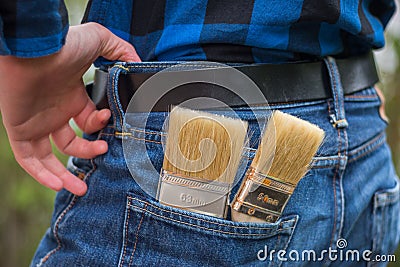 Home handyman: Rear view of a young man with paint brushes in his pocket Stock Photo