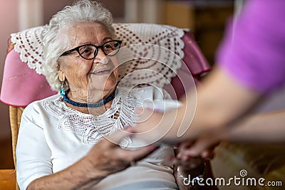 Home healthcare nurse gives a senior female a cup of hot tea Stock Photo