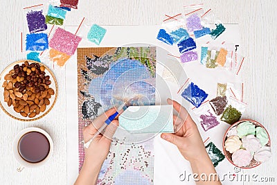 Home hobby to draw a picture of rhinestones, multicolored diamond mosaic. the process of gluing a pencil of rhinestones on the Stock Photo