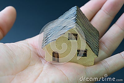 Home / house, real estate or residential concept, miniature ceramic house in real human female hand with dark background Stock Photo