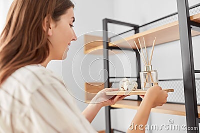 Woman placing aroma reed diffuser to shelf home Stock Photo