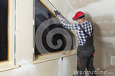 Home improvement handyman installing window in new build attic by using leveler and laser leveler Stock Photo