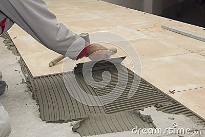 Home improvement, renovation - construction worker tiler is tiling, ceramic tile floor adhesive, trowel with mortar Stock Photo