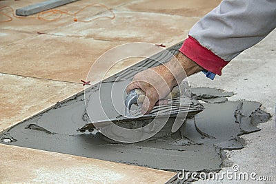 Home improvement, renovation - handyman laying tile with level Stock Photo