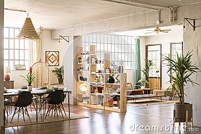 Home indoors. Open space with living room and dining room in bright industrial loft with green plants. Stock Photo