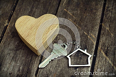 Home key with house keychain and wooden heart mock up on vintage wood background, home sweet home concept Stock Photo