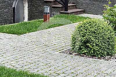 Home landscaping. Backyard with granite paving stones, green grass and street lights. Stock Photo