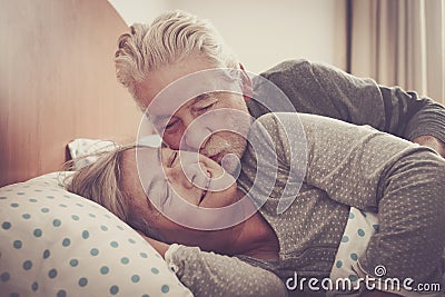 Home lovely scene with couple of senior kissing in the bedroom at the morning ready to wake up and start the day together forever Stock Photo