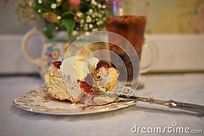 Vintage afternoon tea with floral crockery and scone with cream and jam Stock Photo