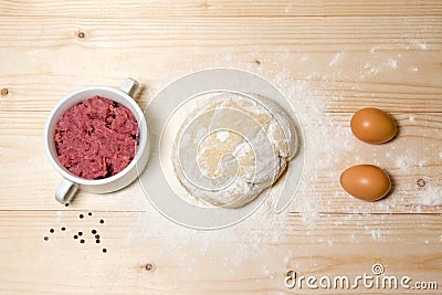 Home-made dough, prepared meat, eggs, flour on a wooden background. Products for cooking dumplings, dumplings with meat. Home Stock Photo