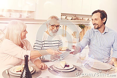 Positive aged parents enjoyign meal with their adult son Stock Photo