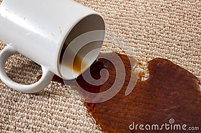 Home mishap, stained carpet, and domestic accident concept with close up of a spilled cup of coffee leaving a stain on the brown Stock Photo