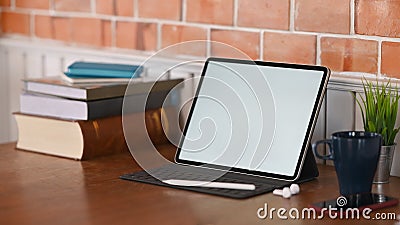 Home office workspace tablet, books, coffee, notebook and plant on wooden table. Stock Photo