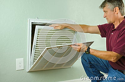 Home owner replacing air filter on air conditioner Stock Photo