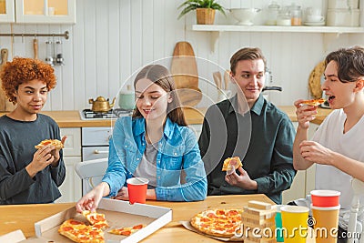 Home party. Overjoyed diverse friends eating ordered pizza for home party. Happy group mixed race young buddies enjoying Stock Photo