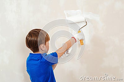 Home renovation. Boy having fun during home renovation. Young boy painting interior wall with paint roller Stock Photo