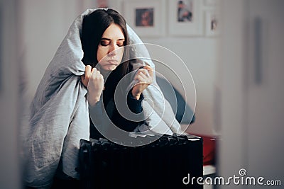 Woman Sitting Next to a Heater with a Blanket on her Head Stock Photo