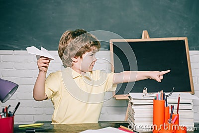 Home or school education. Pupil with paper airplane. Portrait child from elementary school. Stock Photo