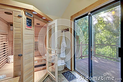 Home walk in large wooden sauna with open door and large deck with green trees Stock Photo
