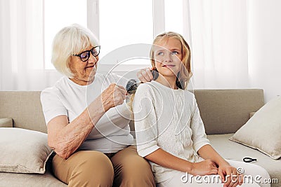 Woman happy couch hair family child love sofa comb home girl granddaughter combing grandmother Stock Photo