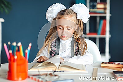 Home work is a difficult task test first grade back to school concept. girl with pigtails and bows in a white blouse shirt leafing Stock Photo