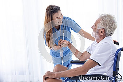 Homecare nurse staff take care elder male sitting at wheelchair happy smile together at home Stock Photo