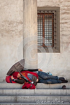 Homeless barefooted man sleeps on a stairway Editorial Stock Photo