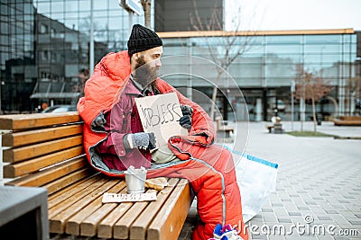 Homeless beggar on the bench near the business center Stock Photo