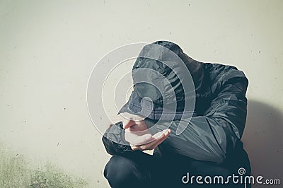 Homeless beggar man drug and alcohol addict sitting alone and depressed on the street in winter clothes feeling anxious cold and l Stock Photo