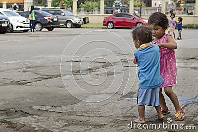 Homeless beggar`s children boy and girl, walking, take care of each other at church yard Editorial Stock Photo