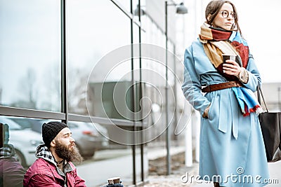 Homeless begging money to a passing by woman Stock Photo