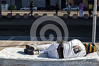 A homeless black man asleep on the old sofa in the street Editorial Stock Photo