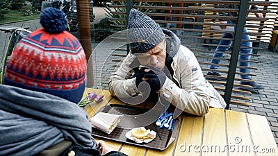 Homeless couple, man and woman eating leftovers from a table in a street cafe Stock Photo