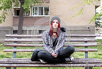 Homeless girl, Young red hair girl sitting alone outdoors with hat and shirt anxious and depressed after she became a homeless Stock Photo