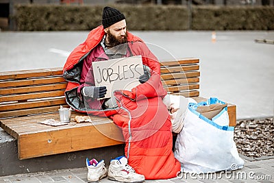 Homeless beggar on the bench near the business center Stock Photo