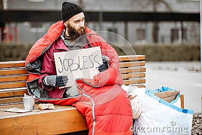 Homeless beggar on the bench near the business center Stock Photo