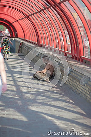 The homeless man asks for alms, people pass by Editorial Stock Photo