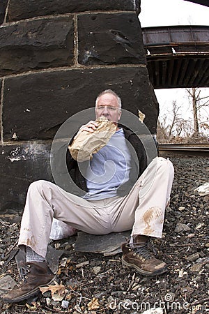 Homeless man drinking under railroad bridge Stock Photo